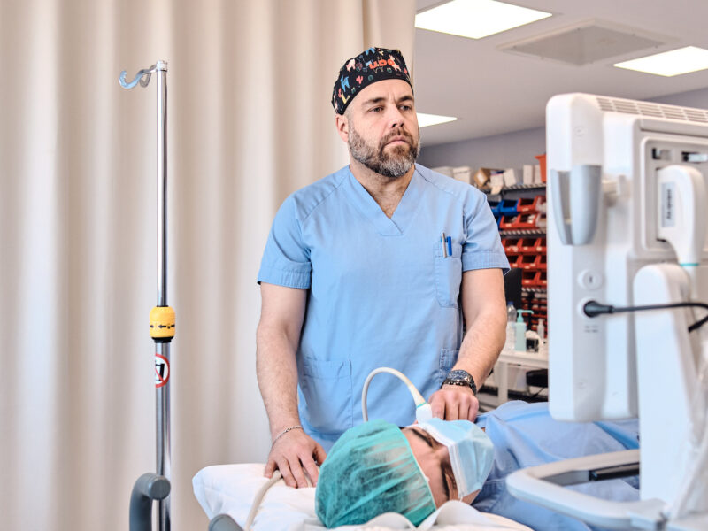 Médico realizando un bloqueo nervioso guiado por ecografía para cirugía de hombro.