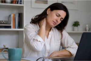 "Mujer con dolor cervical crónico tocándose el cuello"