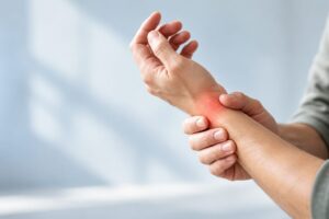 Persona con dolor de tendinitis en la muñeca sujetándose el antebrazo